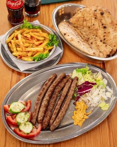 Ćevapi auf einer Metallplatte mit Salat und Brot